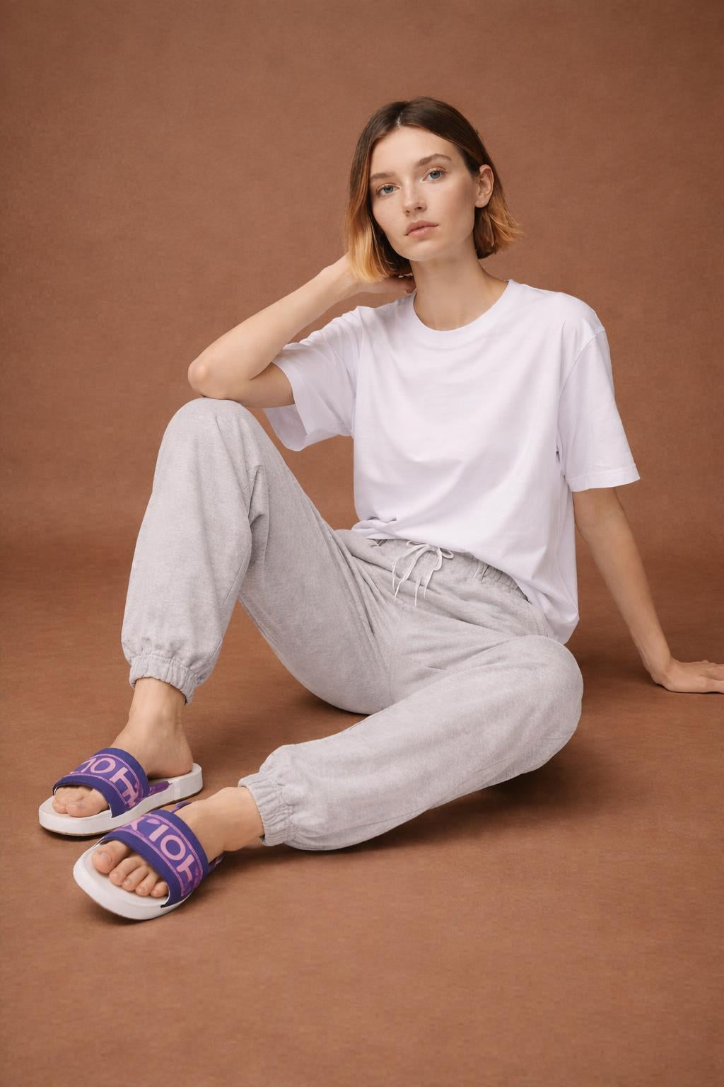 Model sitting while wearing HOLY slides